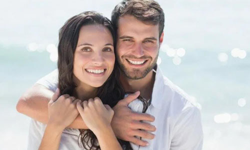 Picture of a man,  happy with his hair transplant  procedure he had in Cabo San Lucas, Mexico.  The man is shown with his arm around a woman and both are smiling at the camera.