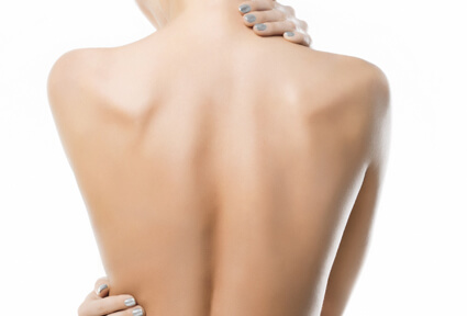 Picture of a woman with her back to the camera and happy with her perfect back liposuction procedure she had with top plastic surgeons in beautiful Cabo San Lucas, Mexico.  She has two hands positioned to highlight the areas of her back liposuction.