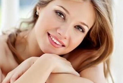 Picture of a trim woman sitting with arms crossed, and happy with her perfect Labiaplasty she had with top plastic surgeons in beautiful Cabo San Lucas, Mexico.  The woman has long sandy blonde hair and is facing the camera with head slightly tilted.