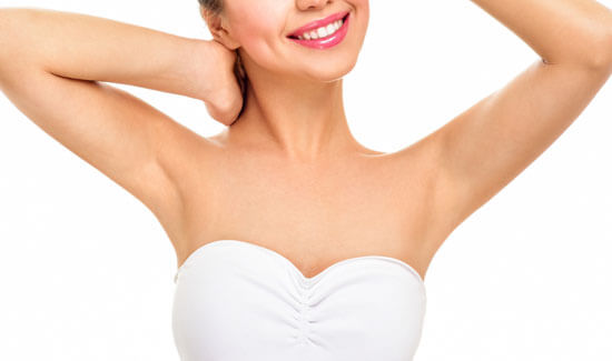 Picture of a woman holding her arms up and happy with her perfect arms liposuction procedure she had with Cabo MedVentures in beautiful Cabo San Lucas, Mexico.  The woman is wearing a white top and smiling to the camera.