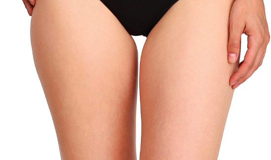 Picture of a trim woman wearing a black bikini bottom, and happy with her perfect thigh lift she had with Cabo MedVentures in beautiful Cabo San Lucas, Mexico.  The woman is facing the camera and has both arms down to her sides.