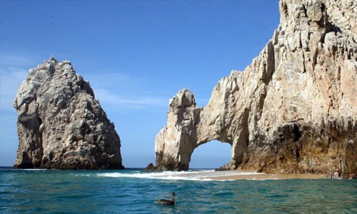 Picture of the Arch of Cabo in Los Cabos, Mexico.  The picture shows two mountainous stone arches arising out of the water in Los Cabos.